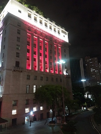 #PraCegoVer: Na foto, o prédio da prefeitura está iluminado com a cor vermelha para simbolizar o "Dezembro Vermelho".